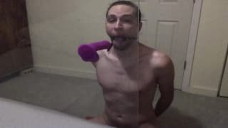 Mec avec une boule-bâillon fait la deepthroat à son gode