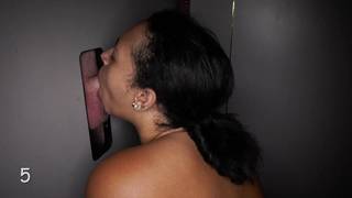 Une brune devant un trou dans le mur suce plusieurs bites à la fois